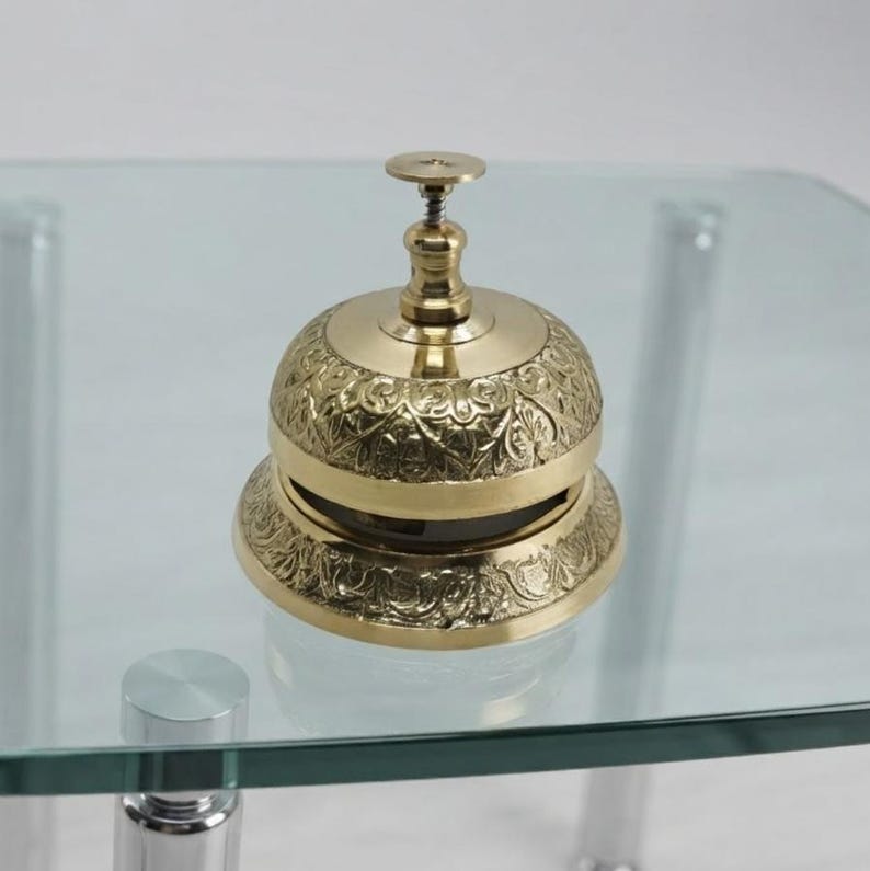 Antique style brass desk bell with engraved pattern and smooth polished surface, elegant decorative accessory for office reception or home decor.