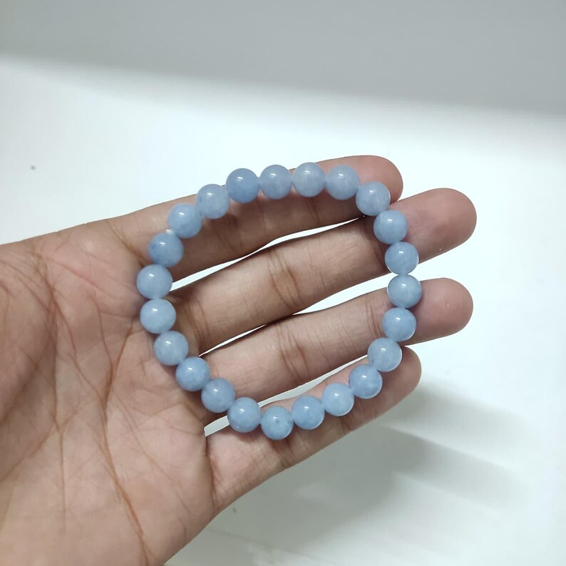 Polished aquamarine gemstone bracelet held gently in an open hand.