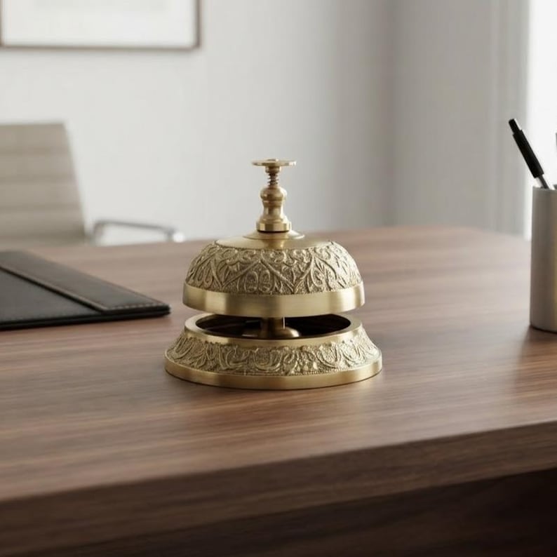 Classic brass service bell featuring push button mechanism and decorative detailing, ideal reception counter bell for hotel lobby or front desk.