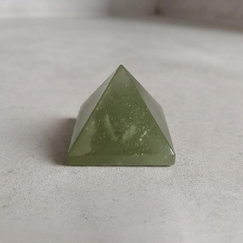 Natural green aventurine pyramid stone displayed as spiritual decor for meditation altar