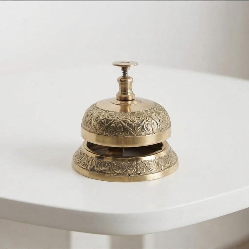 Handmade brass call bell with antique engraved design and polished gold finish, perfect vintage reception desk bell for hotel, restaurant counter or office table decor.