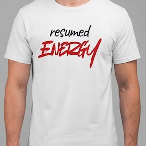 May include: A white short-sleeved t-shirt featuring the word "resumed" in black lowercase letters above the word "ENERGY" in large, bold, red uppercase letters. The design is centered on the chest of the garment, which has a crew neckline.