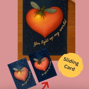 May include: A greeting card with a pull tab, featuring a heart with a firefly and the text "You light up my world." Two smaller cards with the same design are also visible. The words "Sliding Card" are on a yellow circle.