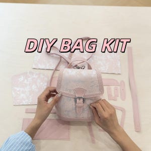 May include: A DIY bag kit with various pink leather pieces and a partially assembled small backpack. The bag features a floral pattern and a silver buckle. The text "DIY BAG KIT" is displayed across the top.