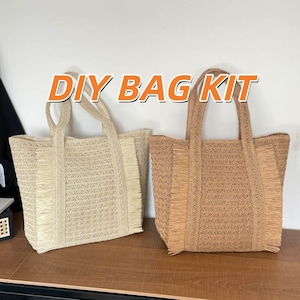 May include: Two woven tote bags, one in a light beige and the other in a medium brown, with fringe detailing and sturdy handles. The bags have the text "DIY BAG KIT" in orange letters.