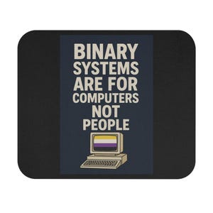 Puede incluir: Alfombrilla de ratón negra con el texto "BINARY SYSTEMS ARE FOR COMPUTERS NOT PEOPLE" en blanco. El diseño incluye un ordenador retro con la bandera del orgullo no binario en la pantalla.