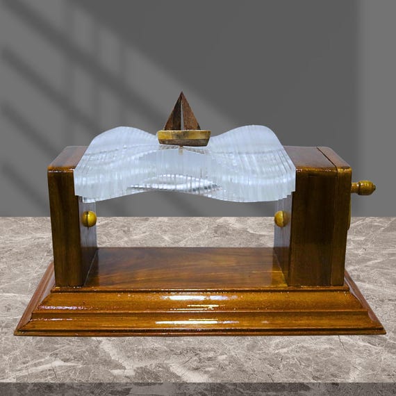 A hand-cranked wooden automaton where a tiny boat rides waves — pure mechanical poetry in carved wood, no batteries needed.