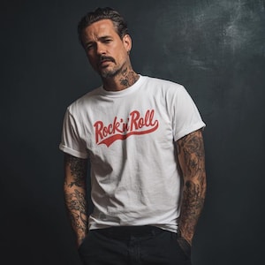 Może przedstawiać: Biała koszulka z czerwonym napisem "Rock 'n' Roll". Koszulka ma krótkie rękawy i klasyczny okrągły dekolt. Zdjęcie przedstawia osobę noszącą koszulkę.