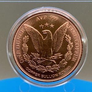 Straight-on view of the copper round's reverse side, featuring the eagle-and-wreath "Copper Bullion Round" design in a protective capsule