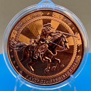 Close-up angled view of the 5 oz .999 fine copper Cowboy round in its protective capsule, showing the raised cowboy-on-horseback design and rope border detail.