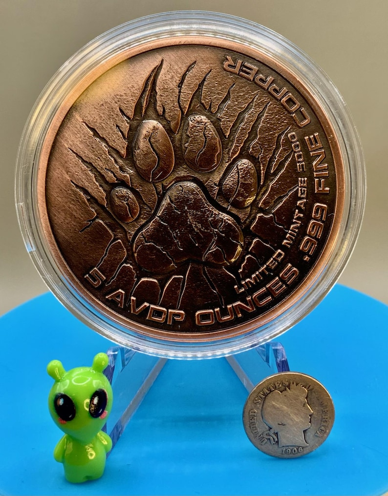 Lion paw print reverse of the copper round on a display stand beside a 1906 Barber dime, showing the round is far larger than a dime