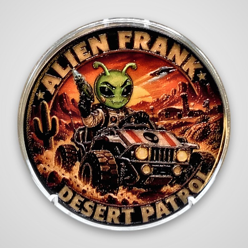 Front of the Alien Frank Desert Patrol 1 oz copper round in a clear capsule, showing a colorized green alien with antennae holding a ray gun and driving an armored desert buggy past cacti under an orange sunset, with "Alien Frank" across the top and "Desert Patrol" along the bottom edge.