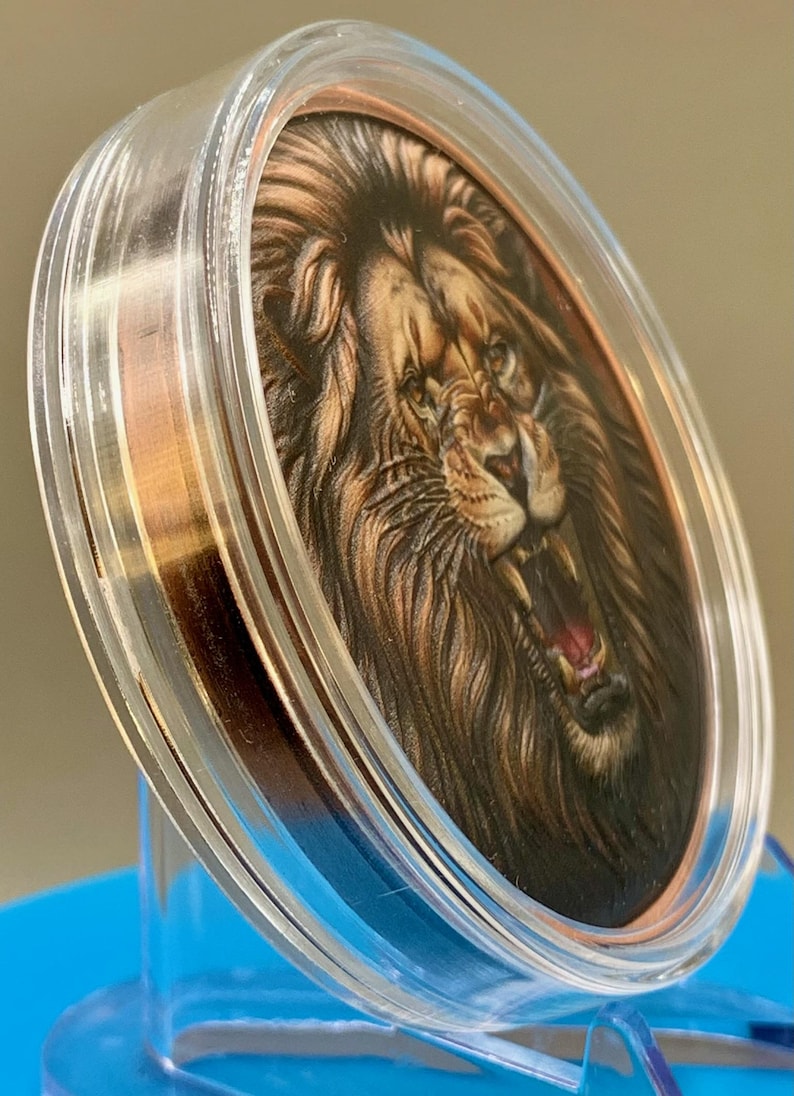 Angled view of the colorized lion obverse in its acrylic capsule, showing the depth of the high relief strike