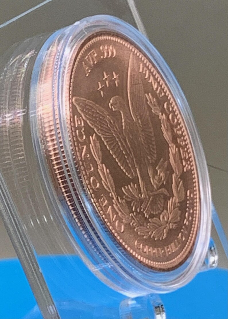 Angled view of the copper round's reverse side, showing the eagle-and-wreath "Copper Bullion Round" design in a protective capsule