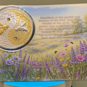 Harmony Bee copper round in its capsule laid on the printed certificate card, which features a wildflower meadow illustration and text reading 5OZ AVDP .999 FINE COPPER, 65mm Radius, Mintage: 10000.