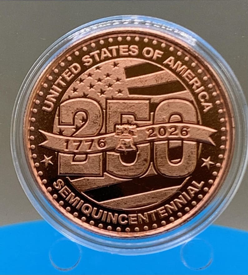 United States of America 250th Anniversary Semiquincentennial copper round featuring Liberty Bell and American flag design, 1776-2026, in protective capsule on blue background
