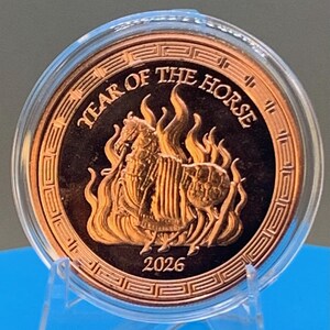 Obverse of the 2026 Year of the Horse copper round in its capsule, showing an armored horse rearing amid flames inside a traditional Greek key border, with YEAR OF THE HORSE lettering above and the 2026 date below.