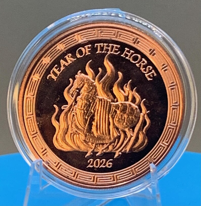 Obverse of the 2026 Year of the Horse copper round in its capsule, showing an armored horse rearing amid flames inside a traditional Greek key border, with YEAR OF THE HORSE lettering above and the 2026 date below.