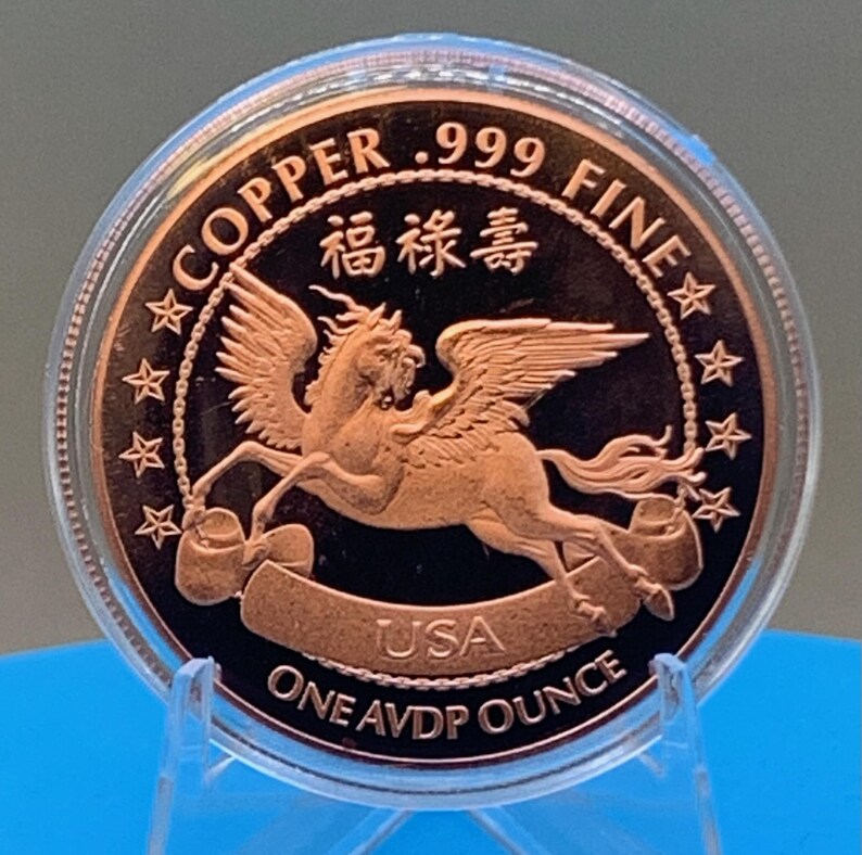2026 Year of the Horse copper round in its protective capsule on a blue stand, Pegasus reverse facing forward with COPPER .999 FINE, USA and ONE AVDP OUNCE lettering.