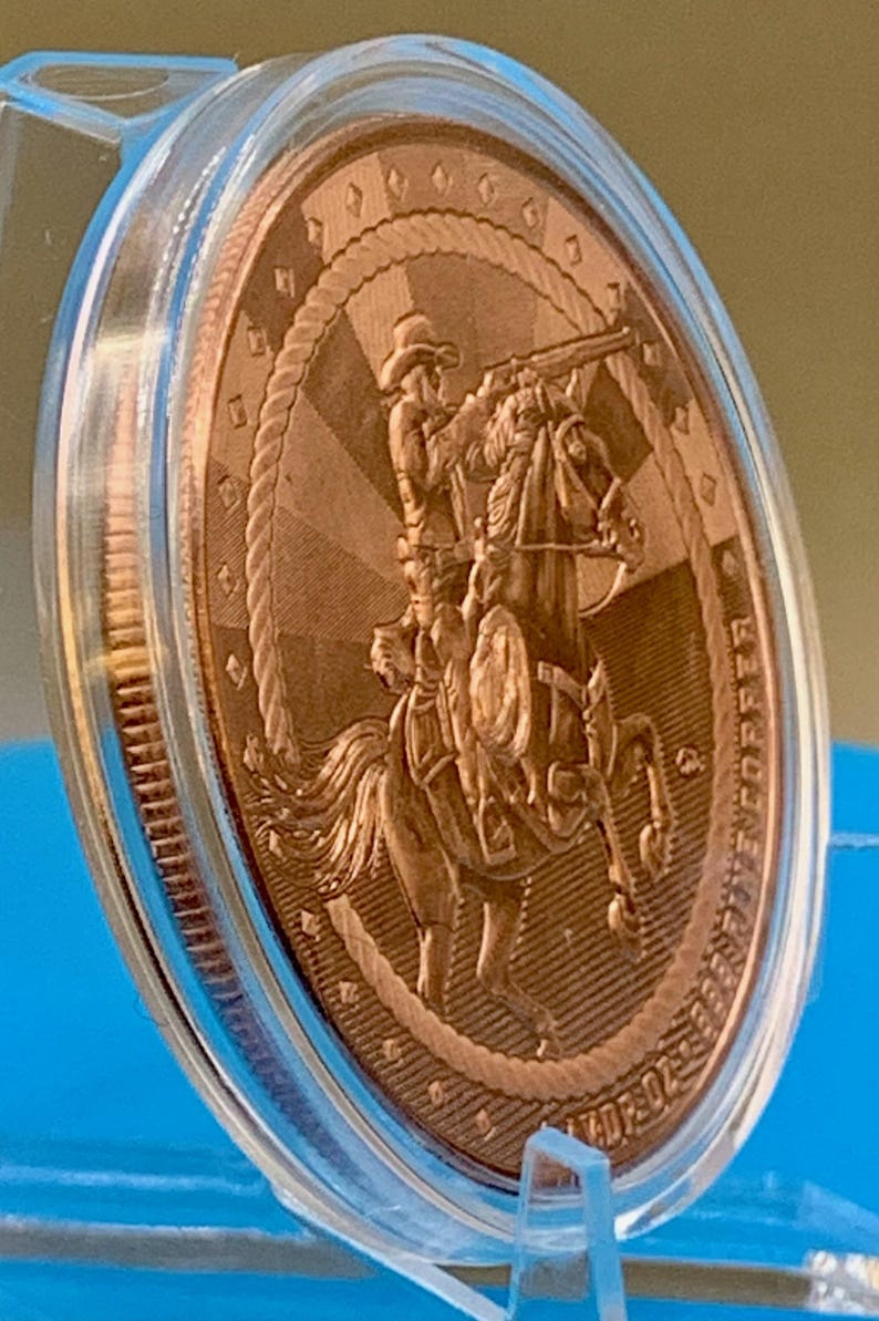 Angled side view of the 5 oz .999 fine copper Cowboy round in its capsule, showing the round's edge and rim detail.