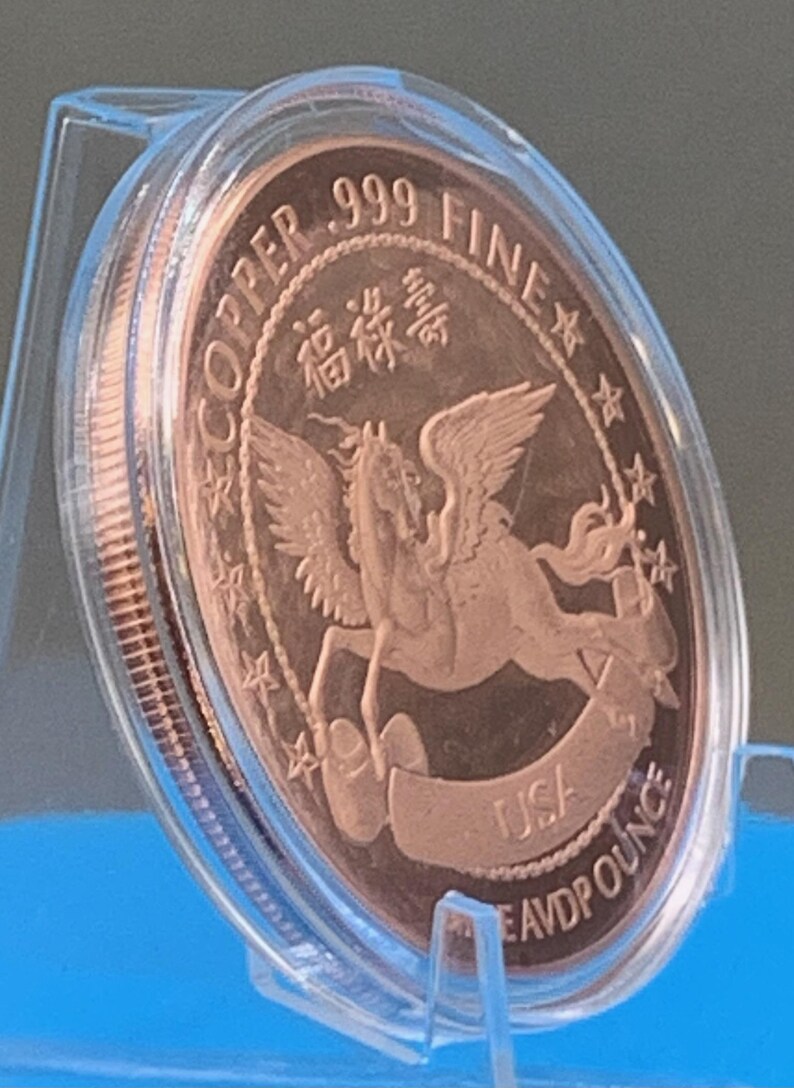 Encapsulated 2026 Year of the Horse copper round tilted on a blue stand showing the Pegasus reverse at an angle, with light catching the high-relief wings and the capsule's reeded rim.