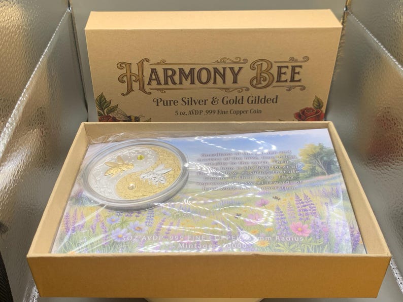 Overhead view of the open Harmony Bee copper round packaging, showing the round in its sealed capsule on top of a printed certificate card inside the box.