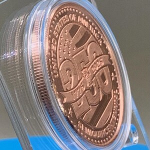 Angled view of United States 250th Anniversary Semiquincentennial copper round in a clear protective capsule, showing the 1776-2026 dates and stars-and-stripes design
