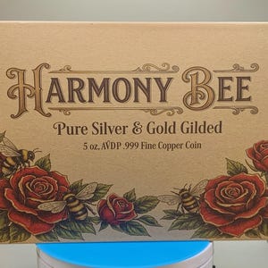 Harmony Bee copper round retail packaging box, kraft-paper lid with rose and bee illustrations, resting on the round's display capsule.