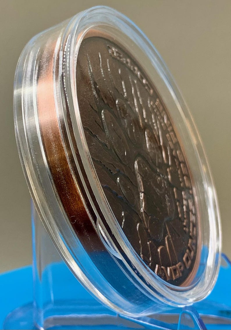 Angled edge view of the paw print reverse in the acrylic capsule, showing the thickness of the 5 oz copper round