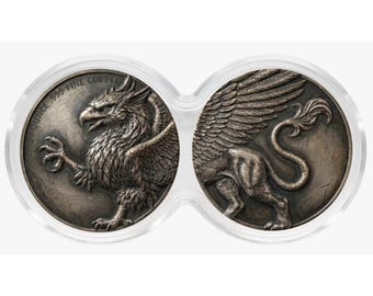 May include: Two circular copper coins encased in a clear plastic holder. The left coin features a griffin with the text OUNCE .999 FINE COPPER. The right coin shows the rear body, wings, and tail of the same griffin in a dark metallic finish.