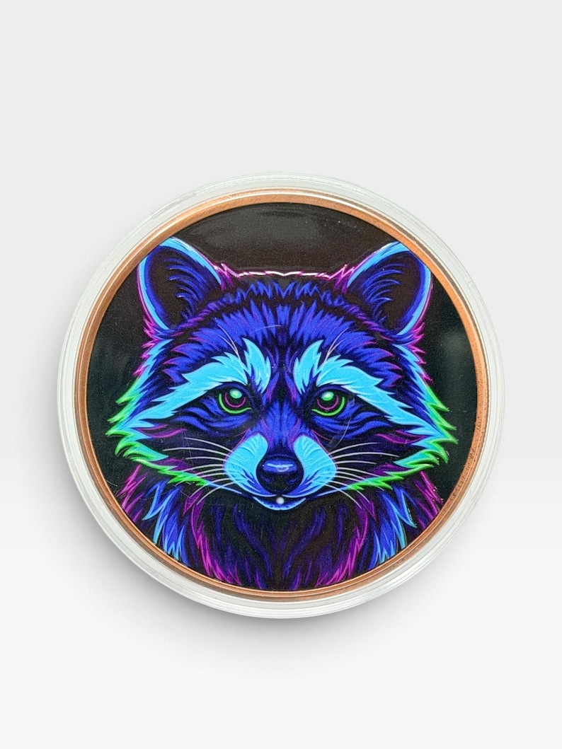 May include: A circular decorative item featuring a vibrant, neon-colored illustration of a raccoon face. The raccoon is rendered in shades of electric blue, purple, and bright green against a dark background, enclosed in a clear, circular frame.