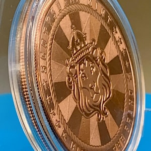 Reverse side of the 5 oz .999 fine copper Cowboy round, featuring a Scottsdale Mint lion crest emblem with the motto "Ride for the Brand" on a radiating sunburst background.