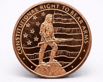 Peut inclure: Une pièce de monnaie de couleur bronze avec l'inscription "CONSTITUTIONAL RIGHT TO BEAR ARMS" sur le bord. Elle représente une personne tenant un fusil, debout sur un rocher, avec un drapeau et des étoiles en arrière-plan. Pièce circulaire.