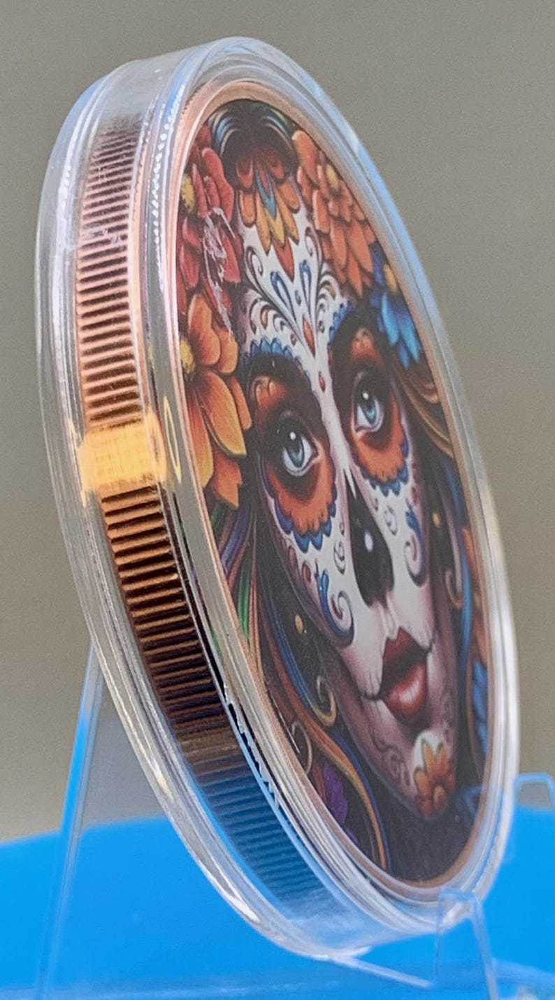 Angled edge view of the Día de los Muertos legal tender copper coin in a clear capsule, showing the coin's thickness and edge detail