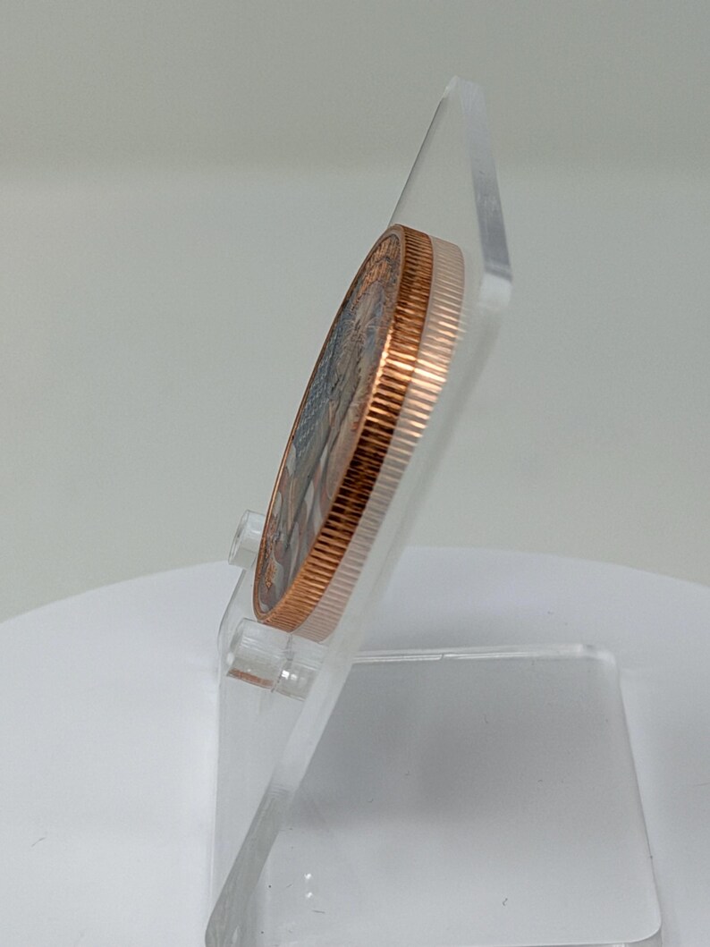 Edge-on side profile of the 1 oz copper round on a clear acrylic stand, showing the coin's thickness and smooth rim