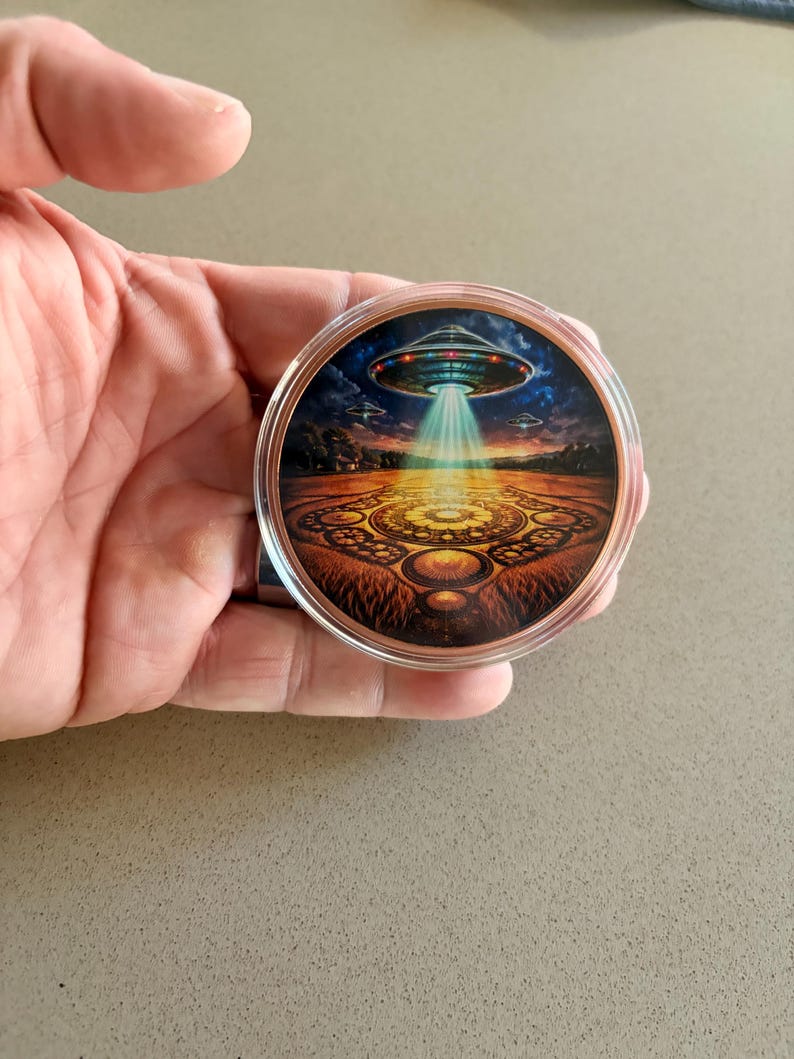 Close-up hero image of a 5 oz colorized copper bullion round featuring alien spacecraft, glowing beam, and crop circle design.