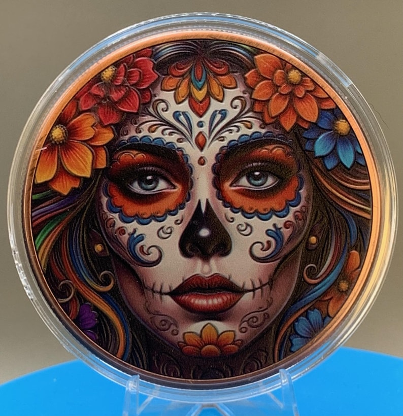 Close-up of the Día de los Muertos legal tender copper coin with a colorful sugar skull face design in a protective capsule