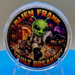 Front of the Alien Frank Vault Breakout 1 oz copper round in a clear capsule, showing a colorized green alien in a space suit pushing a cart of coins through a vault, in orange, red and purple, with "Alien Frank" across the top and "Vault Breakout" along the bottom edge.