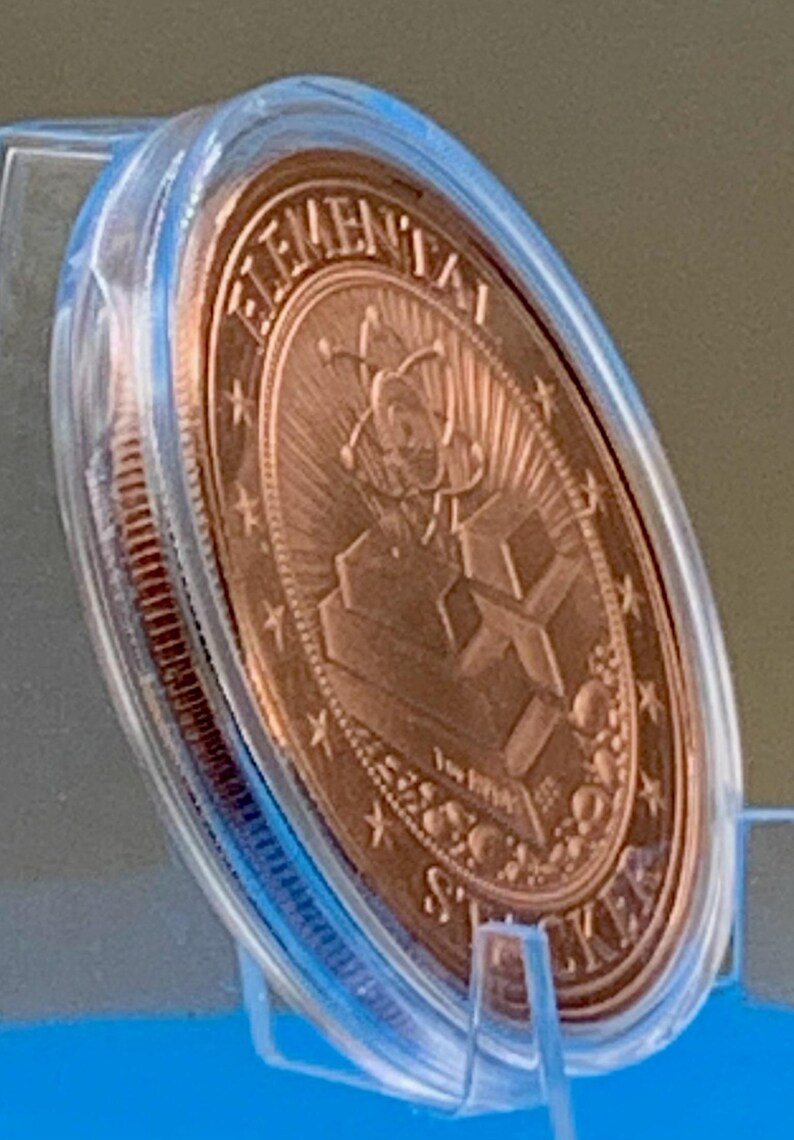 Angled side view of the Night Arrival 1 oz copper round in its capsule, showing the copper reverse and the thickness of the coin