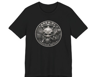 May include: A black short-sleeved t-shirt featuring a circular graphic on the chest. The design depicts a metallic alien character holding a ray gun, with the text AREA 51 and PRECIOUS METALS printed in a circular border around the central figure.