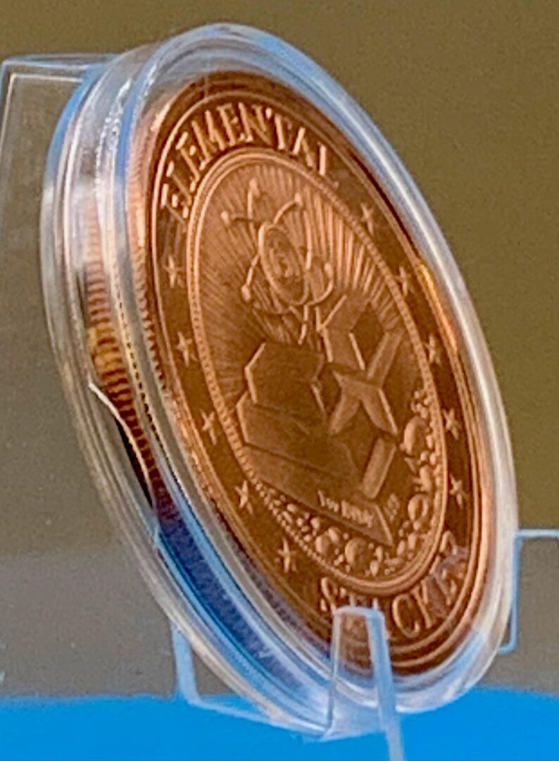Side view of the First Contact 1 oz copper round in its capsule showing the bright copper reverse and the coin thickness