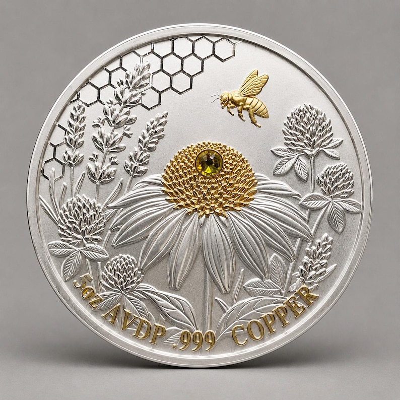 Studio product shot of the reverse side of the Harmony Bee copper round, out of its capsule, showing a gold bee over honeycomb, clover, and coneflower engraving with rim text reading 5oz AVDP .999 COPPER.
