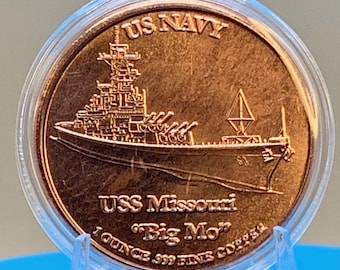以下が含まれることがあります： 透明なプラスチックカプセルに入った丸い銅貨。コインには戦艦ミズーリの浮き彫り画像があり、表面にはUS NAVY、USS Missouri、Big Mo、1 OUNCE .999 FINE COPPERという文字が刻印されています。