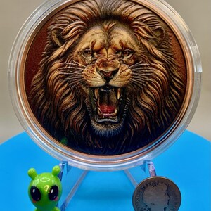 Colorized roaring lion copper round on a display stand, shown beside a 1906 Barber dime for size comparison
