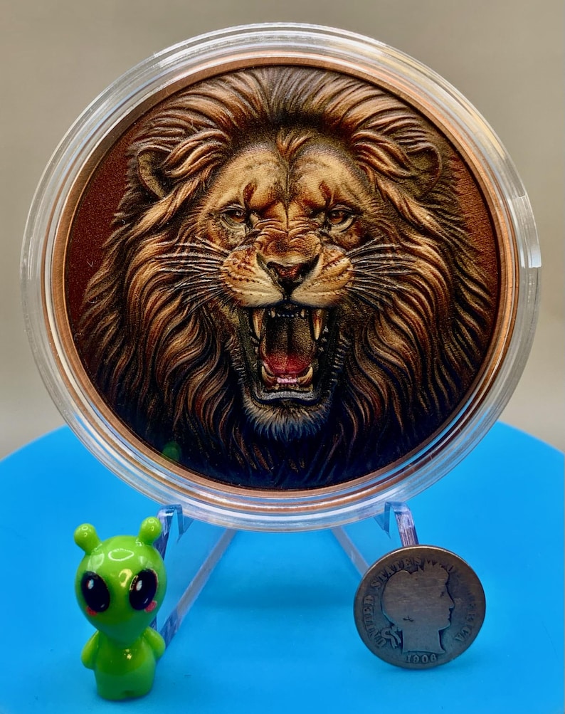 Colorized roaring lion copper round on a display stand, shown beside a 1906 Barber dime for size comparison