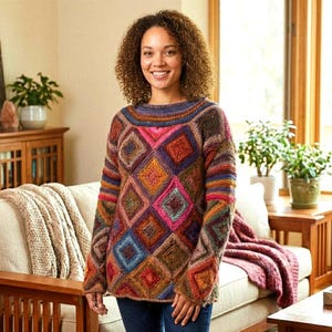 Puede incluir: Un suéter colorido tejido a mano con un patrón geométrico de diamantes. El suéter presenta una variedad de colores, incluyendo rosa, naranja, azul y marrón. El cuello y las mangas tienen detalles a rayas. El suéter es usado por una persona.