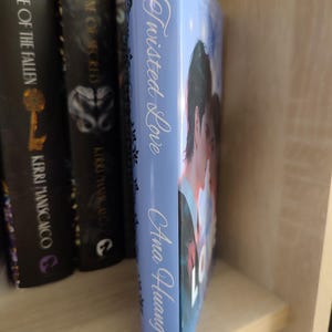 Pu&ograve; includere: Dorso di libro azzurro con il titolo "Twisted Love" di Ana Huang in scrittura bianca. Il libro &egrave; accanto ad altri libri su uno scaffale. La copertina mostra una coppia. Il libro fa parte di una serie.