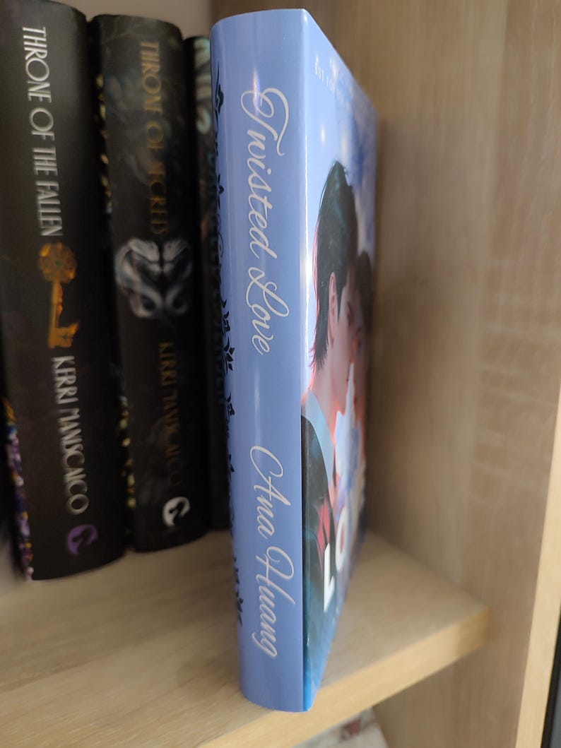 Pu&ograve; includere: Dorso di libro azzurro con il titolo "Twisted Love" di Ana Huang in scrittura bianca. Il libro &egrave; accanto ad altri libri su uno scaffale. La copertina mostra una coppia. Il libro fa parte di una serie.