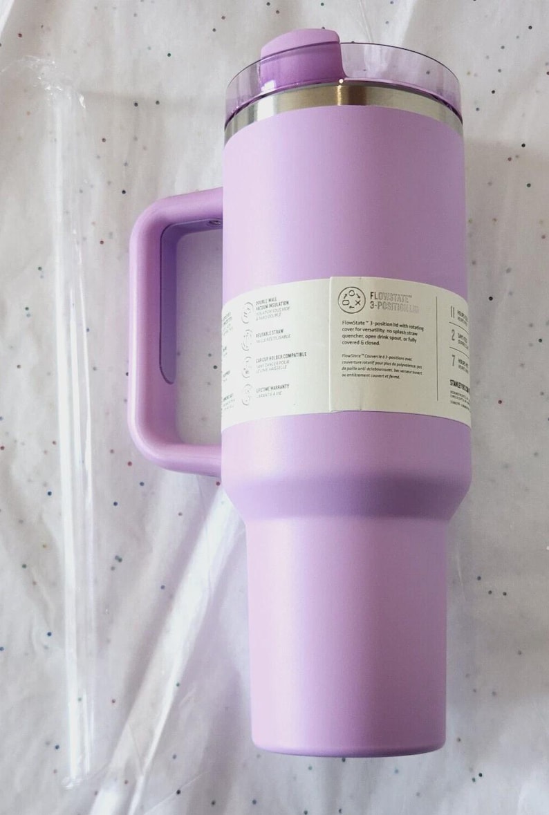 Puede incluir: Un vaso t&eacute;rmico aislado de color lavanda con asa y tapa transparente. El vaso tiene un borde de acero inoxidable y una pajita transparente. Una etiqueta lateral proporciona informaci&oacute;n del producto. Est&aacute; dise&ntilde;ado para mantener las bebidas fr&iacute;as.