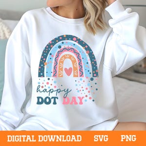 May include: White sweatshirt with a colorful rainbow graphic and the words "happy DOT DAY". The rainbow design includes blue, pink, and orange hues with a heart in the center. The design is surrounded by colorful dots.
